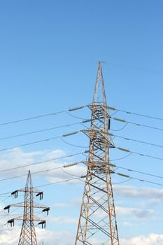 two electric pillars and a lot of cables in blue cloudy sky