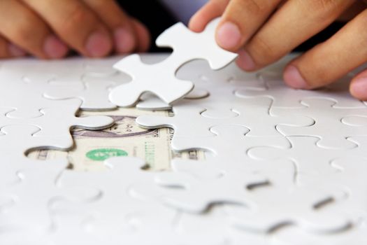 business man hand holding a puzzle piece, money concept