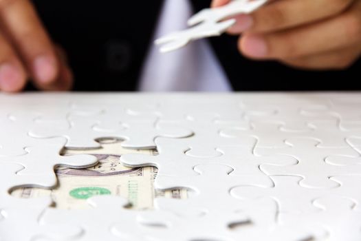 business man hand holding a puzzle piece, money concept