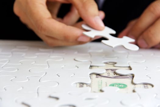 business man hand holding a puzzle piece, money concept