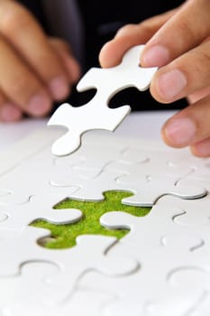 business man hand holding a puzzle piece, green space concept