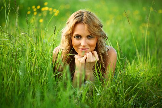 blonde lays on green grass