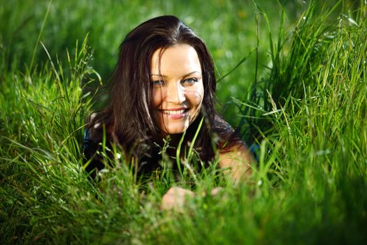 brunette lays on green grass