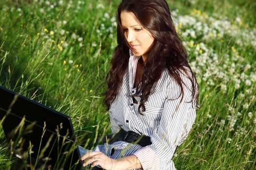 woman on green field work on laptop