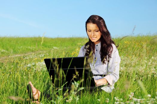 woman on green field work on laptop