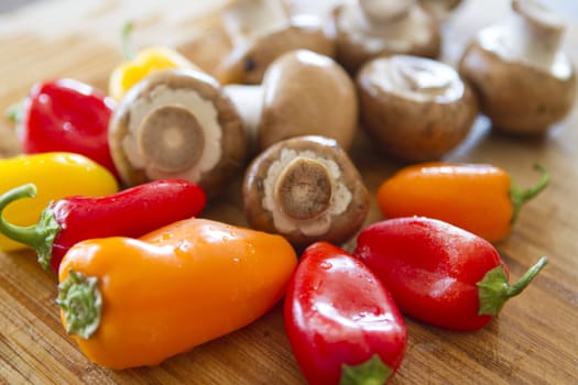 Mushrooms and colorful peppers will get cut momentarily on a wet bamboo cutting board after they take their shower.