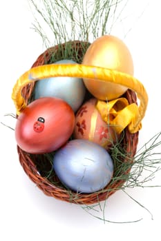 Colorful painted easter eggs in basket on white