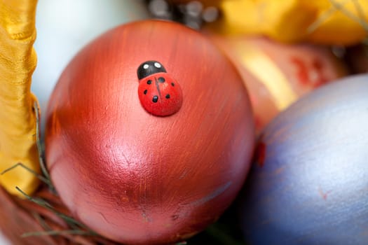 ladybug on painted easter eggs in basket, closeup
