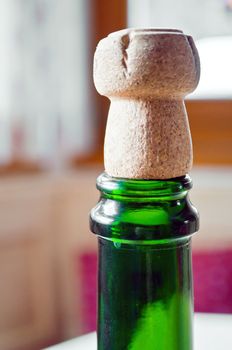 Opened champagne plug over a green bottle