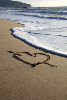 Valentine's Day heart with cross on the beach horizontal with sea going to canel it