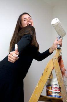 beautiful italian woman showing thumb up while painting a white wall