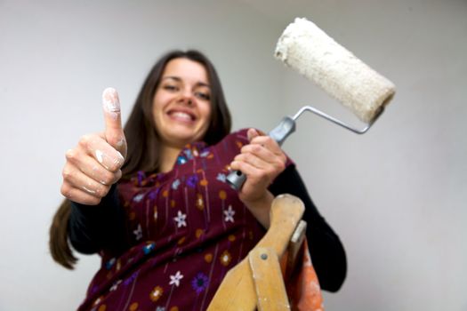 white thumb up while painting a white wall