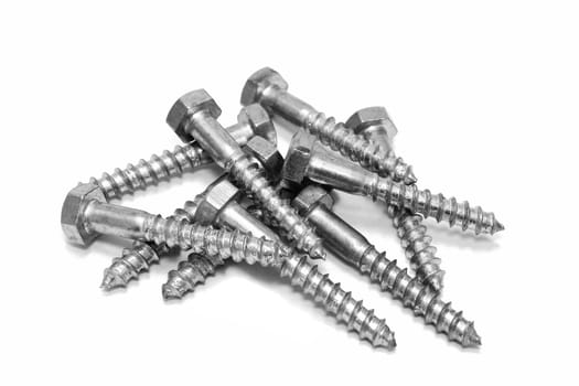Random pile of hexagonal threaded steel bolts or screws on white
