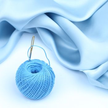 thread on blue silk isolated close up