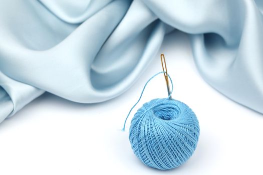 thread on blue silk isolated close up