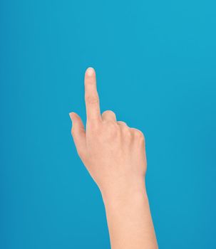 Hand making a touch gesture as though touching an interface or touchscreen or a pointing with one finger isolated against a blue background
