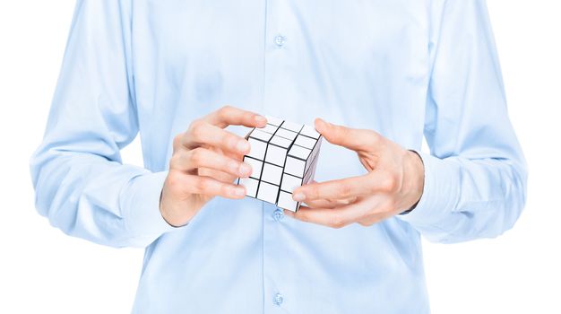 Cropped view of the torso and hands of a man holding a blank white cubic twist puzzle game which he is trying to solve. Isolated on white.