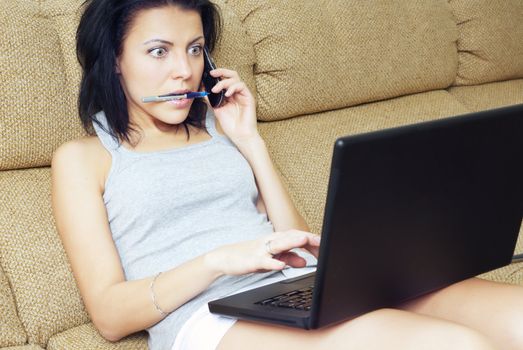 Busy woman talking via cell phone and operating a laptop