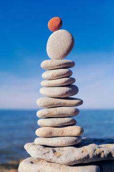 Balancing red stone on the top of pile of pebbles