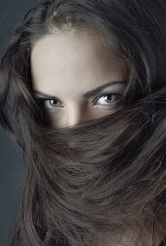Close-up portrait of the woman face covered by her hairs