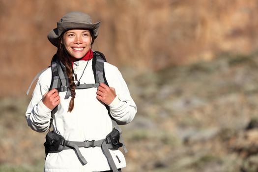 Hiking - woman hiker walking outdoors in mountain landscape smiling happy looking at copy space. Multiracial Asian Caucasian female model outdoors.
