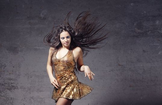 Active woman with long hair dancing on a trash background