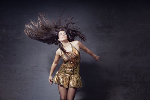 Woman dancing and moving her long hairs on a trashy background
