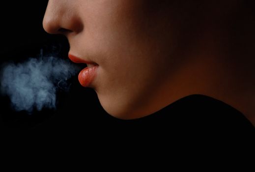 Half-face of the smoking woman on a black background