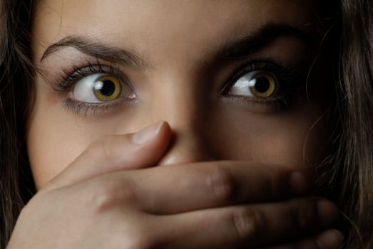 Close-up portrait of woman with mouth closed by the hand