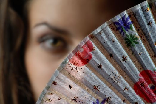 Fashion colored fan and out-of-focus face of the woman