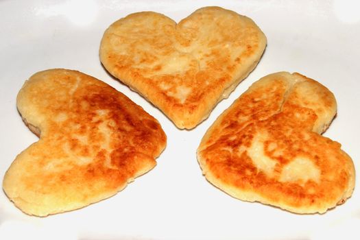 Cheese pancakes in form hearts. Isolated on white background. Love