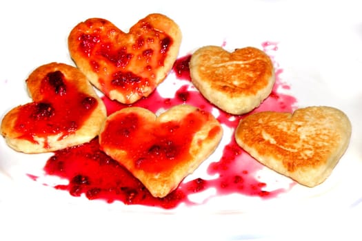 Cheese pancakes in form hearts.with arrow from srawberry jam Isolated on white background. Love
