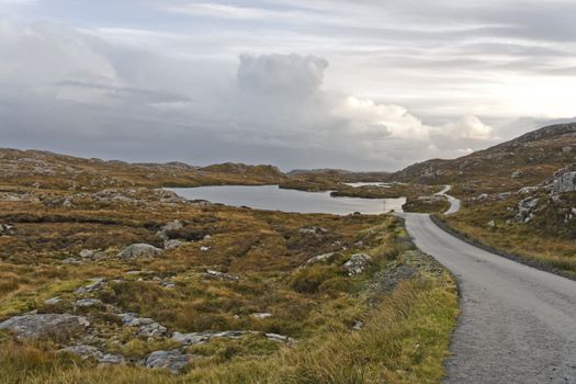 single track road on scottish isle. heathlands and loch