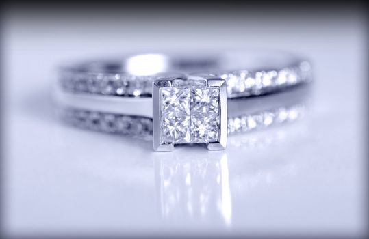 Closeup shot of a diamond engagement ring shot on a grey background.