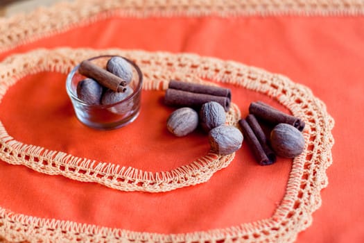 Several nuts and cinnamons on two orange napkins on a wood table
