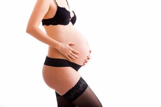 Pregnant woman wearing lingerie holding her belly