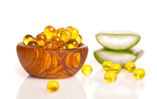 Cod liver oil omega, gel capsules in the wooden bowl. isolated on white background