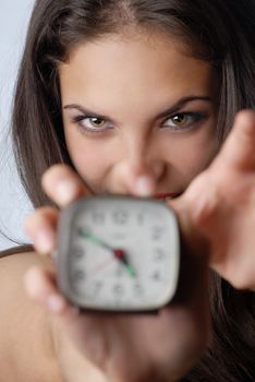 Young angry woman trying to break the alarm-clock