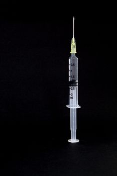 isolated syringe with needle and water drop on black background