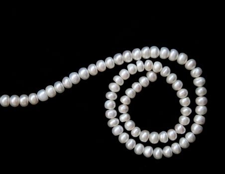 White pearls on the black velvet background 