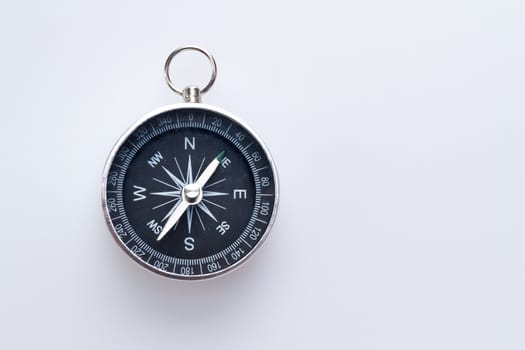 a simple metal compass hanged on white surface with copy space