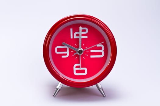 close up view of red clockface in the center of landscape orientation with shite background