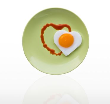 Fried egg heart and sauce heart on green dish