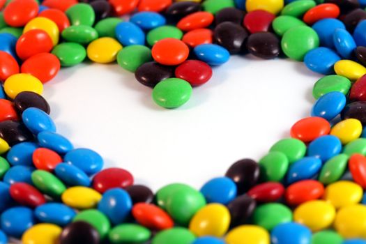 Colorful candies with whitespace forming a heart.