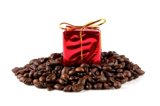 A gift resting upon a pile of coffee beans. Studio shot on a solid white background.