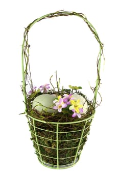 A decorative easter basket with easter eggs and flowers. Shot was taken on a solid white background.