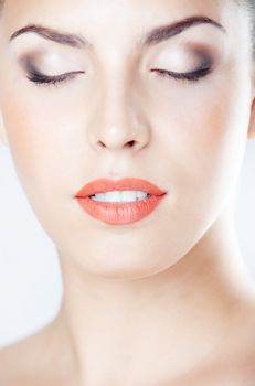 Beautiful lady with perfect makeup closes eyes on a studio background