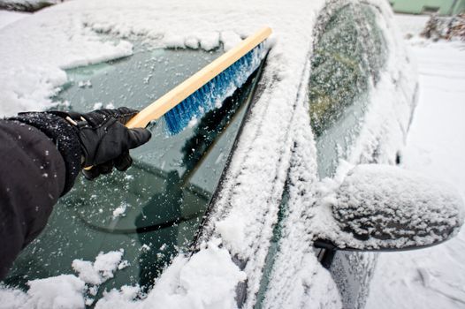 Removing snow from a car window using a brush