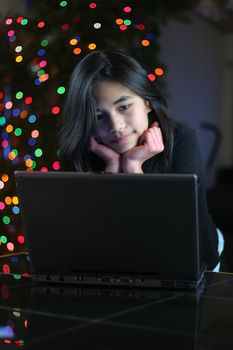 Young teen girl working on the laptop at night.