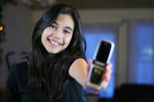 Young teen girl proudly holding out her first cell phone.